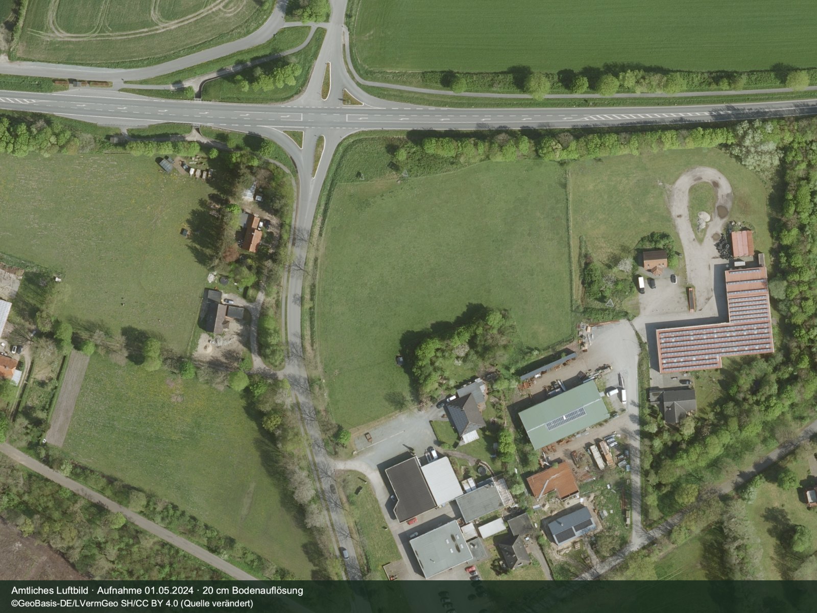 Amtliches Luftbild vom Mai 2024: das unbebaute Grundstück an der Einmündung Dorfstraße/B199, Bundesstraße am oberen Bildrand, angrenzender Gewerbebetrieb im Südosten